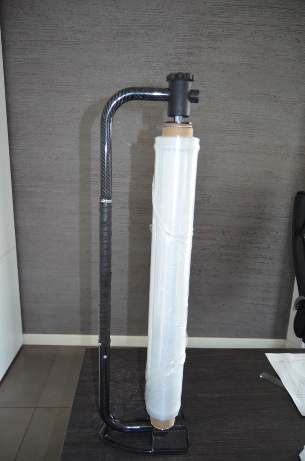 The Hyper Wrap dispenser stood on a desk with a full roll of film on it, the whole carbon handle in frame, and the roll's 620 mm film width marked off down the side of it